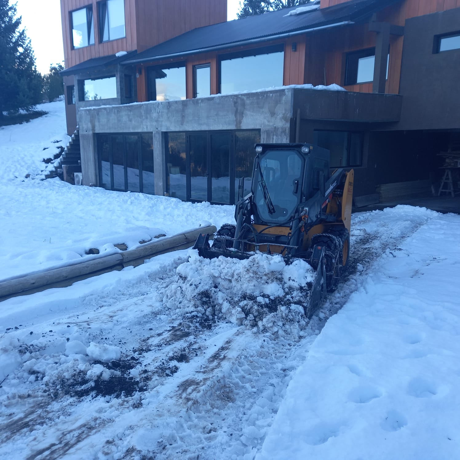 Minicargadora de Salvagno despejando la nieve frente a una casa en San Martín de los Andes
